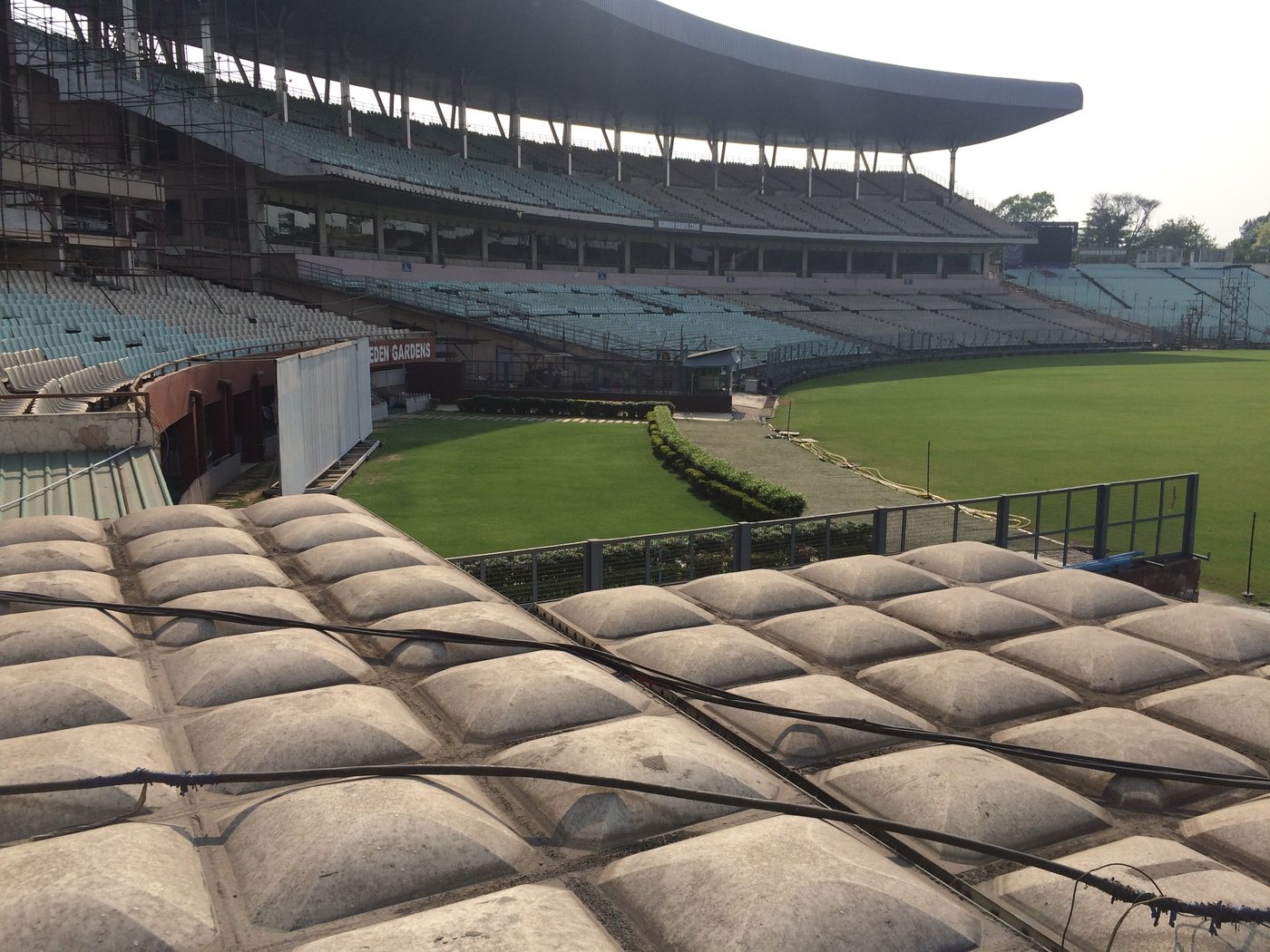 Empty roofed seating tiers and the edge of the outfield at Eden Gardens